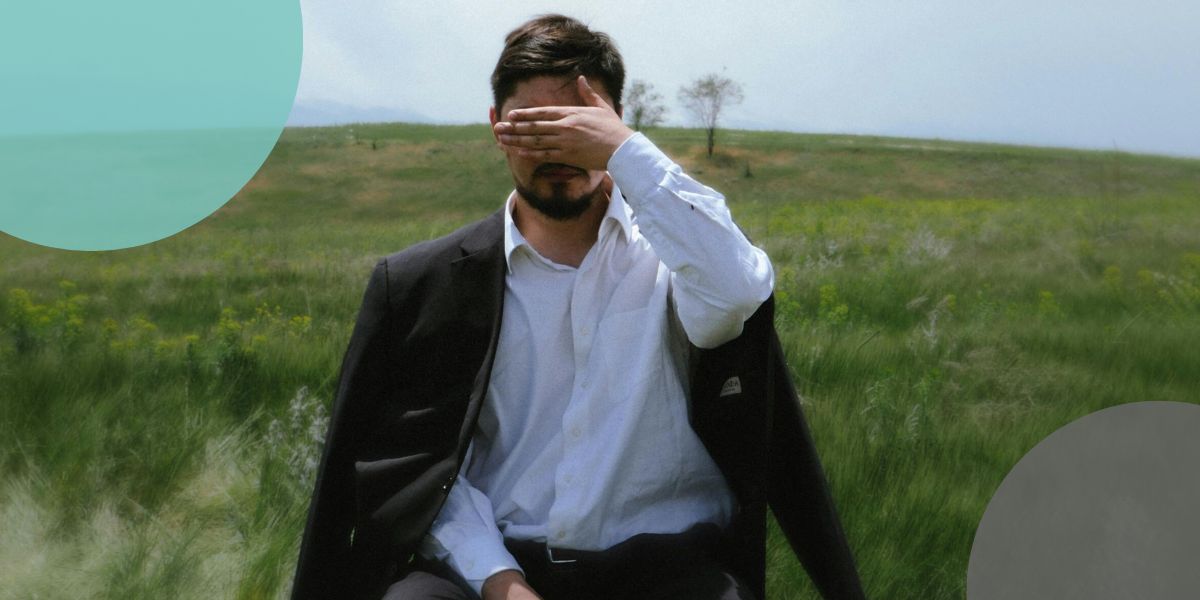 Man in suit covering his face suffering with Imposter Syndrome