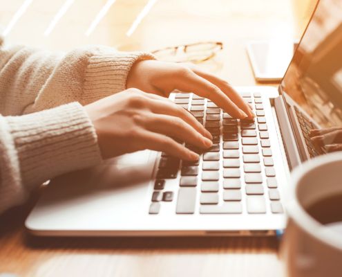 Woman's hands typing on a laptop